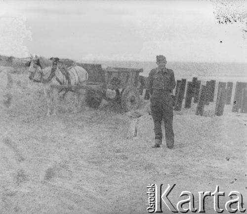 Czerwiec 1946, Dunkierka, Francja.
Żołnierz 2. Dywizji Strzelców Pieszych st. sierż. Jerzy Konrad Maciejewski stoi przy zaporach przeciwdesantowych, będących częścią umocnień 