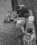 1942-1944, Münchenbuchsee, Szwajcaria.
Dzieci pomagają mężczyźnie pakować do mniejszych pudełek prawdopodobnie drewniane pionki do gry w warcaby.  
Fot. Jerzy Konrad Maciejewski, zbiory Ośrodka KARTA 
