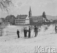 1940-1941, Münchenbuchsee, Szwajcaria.
Dzieci podczas jazdy na nartach. Za nimi widać budynki miasteczka i górującą  nad nimi wieżę kościoła.
Fot. Jerzy Konrad Maciejewski, zbiory Ośrodka KARTA