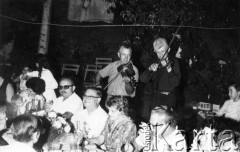Wrzesień 1969, Posadas, Misiones, Argentyna.
25-lecie święceń ojca Casimiro w domu brata Juana. Na skrzypcach grają Tomas Kurpaska (po lewej) i Antonio Skupień. Przy stole siedzą od lewej: Ladislao Mazur, ojciec Casimiro Kalafarski, Helena Kalafarski de Skupień, Juan Sendlak i jego małżonka Lidia Kalafarski.
Fot. NN, zbiory Asociación Polaca de Posadas, udostępniła Fabiana Śniechowski, reprodukcje cyfrowe w Bibliotece Polskiej im. Ignacego Domeyki w Buenos Aires (Biblioteca Polaca Ignacio Domeyko) i w Ośrodku KARTA w Warszawie