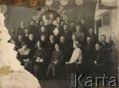 Ok. 1920, brak miejsca.
Prawdopodobnie uczestnicy przedstawienia na tle dekoracji z wizerunkiem orła białego w koronie i napisem 