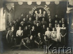 Ok. 1920, brak miejsca.
Aktorzy i muzycy tle dekoracji z wizerunkiem orła białego w koronie i napisem 
