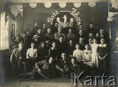 Ok. 1920, brak miejsca.
Aktorzy i muzycy tle dekoracji z wizerunkiem orła białego w koronie i napisem 