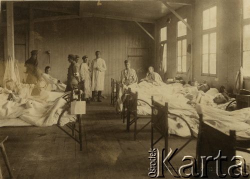 1917, Szczypiorno k. Kalisza.
Niemiecki obóz dla internowanych jeńców wojennych - polskich legionistów w Szczypiornie. Chorzy jeńcy i sanitariusze w izbie szpitalnej. W prawym dolnym rogu podpis: 