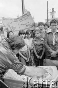 30.07.1981, Łódź, Polska.
Marsz głodowy - jeden z wielu protestów zorganizowanych w kilkunastu miastach Polski na przełomie lipca i sierpnia 1981 roku. Protesty były spowodowane problemami w zaopatrzeniu, zmniejszeniem kartkowych przydziałów mięsa oraz podwyżką cen. Marsz w Łodzi był najliczniejszy. Uczestniczyły w nim głównie kobiety z dziećmi. Na zdjęciu uczestnicy marszu na Placu Wolności, na pierwszym planie kobieta z niemowlęciem w wózku.
Fot. Tomasz Tomaszewski, zbiory Ośrodka KARTA