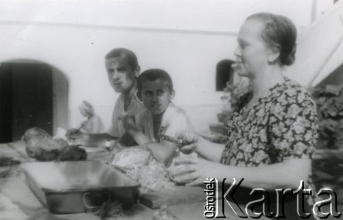 Lata 40., Rumunia.
Polscy uchodźcy w Rumunii podczas II wojny światowej - kobieta szatkująca kapustę, z lewej siedzą dwaj przyglądający się jej chłopcy.
Fot. NN, zbiory Ośrodka KARTA