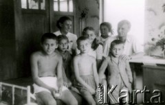 Lata 40., Rumunia.
Polscy uchodźcy w Rumunii podczas II wojny światowej - trzech chłopców i trzy dziewczynki oraz młoda kobieta i chłopak siedzą w pokoju na łóżku.
Fot. NN, zbiory Ośrodka KARTA
