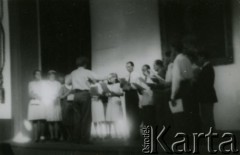 Lata 40., Rumunia.
Polscy uchodźcy w Rumunii podczas II wojny światowej - chór mieszany na scenie w czasie występu, tyłem do obiektywu stoi dyrygent.
Fot. NN, zbiory Ośrodka KARTA