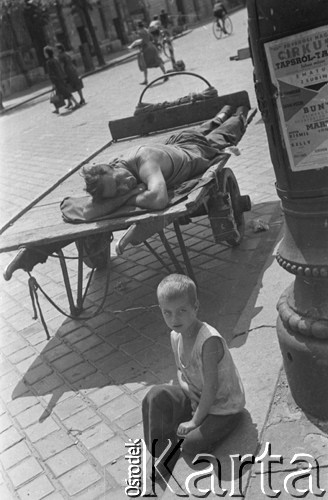 1957, Budapeszt, Węgry.
Mężczyzna śpiący na taczce, na pierwszym planie chłopiec w brudnej koszulce, siedzący na schodach.
Fot. Kazimierz Seko, zbiory Ośrodka KARTA