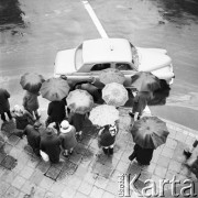 Listopad 1969, Warszawa, Polska.
Przechodnie pod parasolami, ulicą przejeżdża samochód marki 