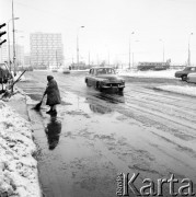 Marzec 1970, Warszawa, Polska.
 Śnieg na ulicach, kobieta zamiatająca przejście dla  pieszych, ulicą jedzie samochód marki 