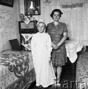 Lipiec 1971, Pawłów Romanów, Polska
 I Komunia święta, dziewczynka z matką, w tle z lewej odbiornik radiowy, na ścianie wisi makatka z napisem 