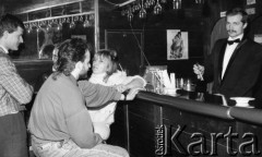 Luty 1988, Ustka, Polska
Grupa osób przy barze, z prawej stoi barman trzymający szczypce do lodu, na ścianie wiszą reklamy Pepsi-Coli.
Fot. Jarosław Tarań, zbiory Ośrodka KARTA [88-31]