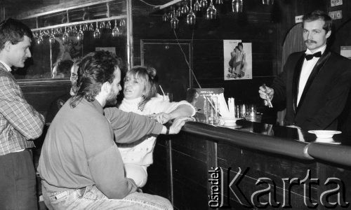 Luty 1988, Ustka, Polska
Grupa osób przy barze, z prawej stoi barman trzymający szczypce do lodu, na ścianie wiszą reklamy Pepsi-Coli.
Fot. Jarosław Tarań, zbiory Ośrodka KARTA [88-31]
