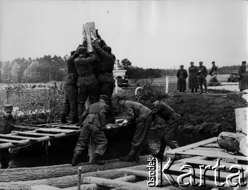 04.1945, miejsce nieznane, Polska.
Budowa drewnianego mostu na rzece [Starej Odrze?]. Polscy saperzy wbijają pal w dno rzeki. Z lewej strony widać fragment skończonego mostu pływającego.
Fot. Józef Rybicki, zbiory Fundacji Ośrodka KARTA