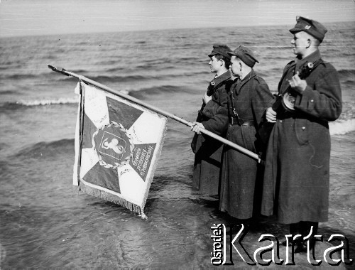 18.03.1945, Kołobrzeg, Polska.
Poczet sztandarowy 10 pułku piechoty w trakcie uroczystości zaślubin z morzem na kołobrzeskiej plaży. Chor. Władysław Spodynek zanurza sztandar w morzu.
Fot. Józef Rybicki, zbiory Fundacji Ośrodka KARTA