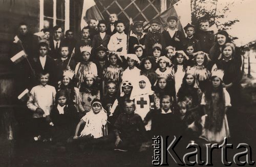 1920-1939, woj. białostockie, Polska.
Uczniowie szkoły powszechnej w przebraniach, kilku chłopców trzyma biało-czerwone chorągiewki, z tyłu dwie polskie flagi.
Fot. NN, zbiory Ośrodka KARTA, udostępniła Janina Bojarska
   
