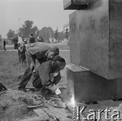 22 lipca–22 sierpnia 1965, Elbląg, woj. gdańskie, Polska.
I Biennale Form Przestrzennych w Elblągu. Montaż rzeźby Antoniego Milkowskiego (1 z lewej) 