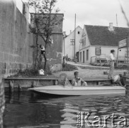 1961, Mikołajki, woj. olsztyńskie, Polska.
Mężczyzna czytający książkę na łódce. W głębi knajpa 