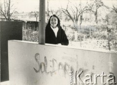 Lata 80., Reszel, Polska.
Kobieta przy murze z napisem 