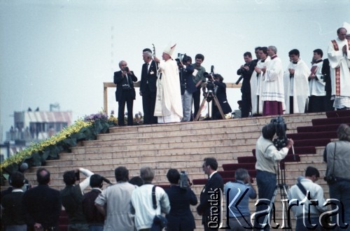 13.06.1987, Łódź, Polska.
Trzecia pielgrzymka papieża Jana Pawła II do Polski w dniach 8-14 czerwca 1987 roku. Msza święta sprawowana przez Ojca Świętego na lotnisku Łódź-Lublinek, podczas której do Pierwszej Komunii Świętej przystąpiło 1600 dzieci. Jan Paweł II pozdrawia wiernych. Obok Ojca Świętego 4. z prawej ksiądz Piero Marini, Mistrz Papieskich Ceremonii Liturgicznych.
Fot. Edward Grochowicz, zbiory Ośrodka KARTA