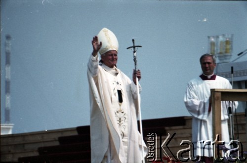 13.06.1987, Łódź, Polska.
Trzecia pielgrzymka papieża Jana Pawła II do Polski w dniach 8-14 czerwca 1987 roku. Msza święta sprawowana przez Ojca Świętego na lotnisku Łódź-Lublinek, podczas której do Pierwszej Komunii Świętej przystąpiło 1600 dzieci. Jan Paweł II pozdrawia wiernych. Z prawej ksiądz Piero Marini, Mistrz Papieskich Ceremonii Liturgicznych.
Fot. Edward Grochowicz, zbiory Ośrodka KARTA