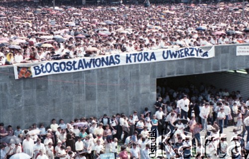 14.06.1987, Warszawa, Polska.
Trzecia pielgrzymka papieża Jana Pawła II do Polski w dniach 8-14 czerwca 1987 roku. Wierni zgromadzeni na mszy świętej sprawowanej przez Ojca Świętego na placu Defilad. Nad przejściem pod ulicą Marszałkowską transparent: 