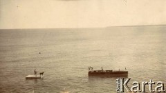 1925-1927, Francja.
Ludzie płynący łódką po morzu w kierunku platformy, na której stoi mężczyzna z psem.
Fot. NN, kolekcja Larysy Zajączkowskiej-Mitznerowej, zbiory Ośrodka KARTA