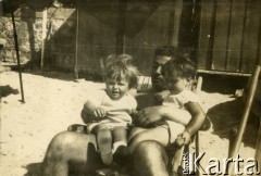 1925-1927, Francja.
Mężczyzna odpoczywa na leżaku na plaży, na kolanach trzyma dwoje dzieci. 
Fot. NN, kolekcja Larysy Zajączkowskiej-Mitznerowej, zbiory Ośrodka KARTA