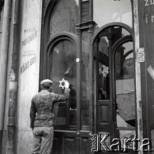 1941, Rzeszów, dystrykt krakowski, Generalne Gubernatorstwo.
Młody mężczyzna malujący gwiazdę Dawida na szybie zakładu księgarskiego i drukarskiego przy ulicy Leszczyńskiego.
Fot. NN, kolekcja Bogusława Kotuli, zbiory Fundacji Ośrodka KARTA