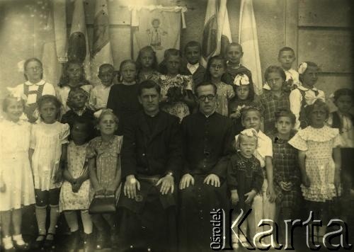 Przed 1939, brak miejsca.
Zdjęcie grupowe dzieci z księżmi.
Fot. NN, zbiory Archiwum Historii Mówionej Ośrodka KARTA i Domu Spotkań z Historią, udostępniła Erika Simaka w ramach projektu 