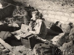 Wiosna 1944, Monte Cassino, Włochy.
Bitwa pod Monte Cassino. Punkt dowodzenia, w środku siedzi oficer brytyjski z mapą i słuchawką telefonu w ręku, za nim siedzi radiotelegrafista. Pod ścianą leży śpiący żołnierz.
Fot. NN, zbiory Instytutu Józefa Piłsudskiego w Londynie.
